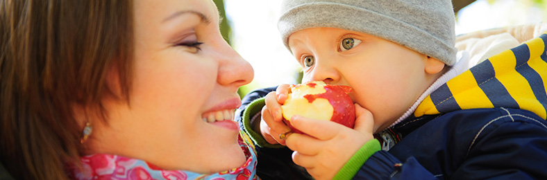 Lähikuvassa äiti ja lapsi, joka syö omenaa.